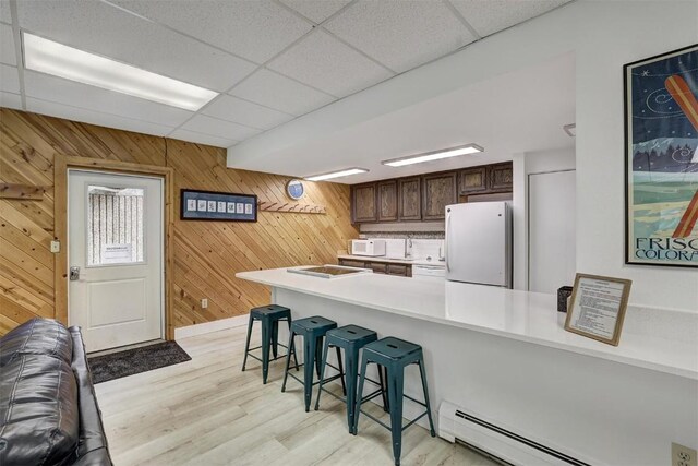 200 Granite St Unit 202, Frisco, CO 80443 - kitchen featuring wooden walls, a baseboard radiator, white appliances, light countertops, and a breakfast bar area