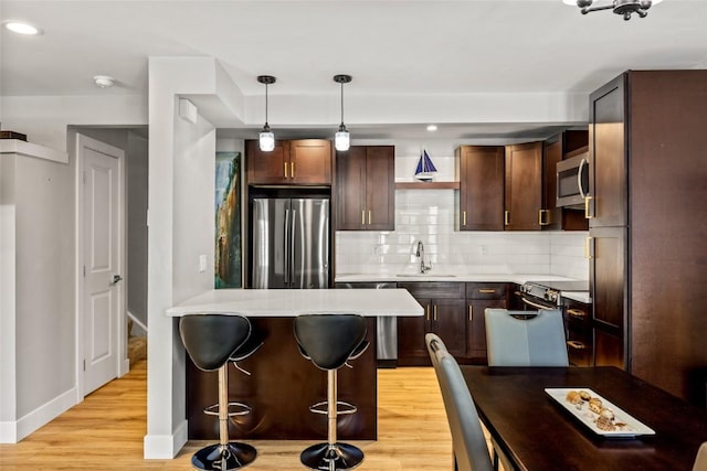 13 Cedar Ct Unit 13, Steamboat Springs, CO 80487 - kitchen with stainless steel appliances, light wood-type flooring, a breakfast bar, light countertops, and decorative backsplash