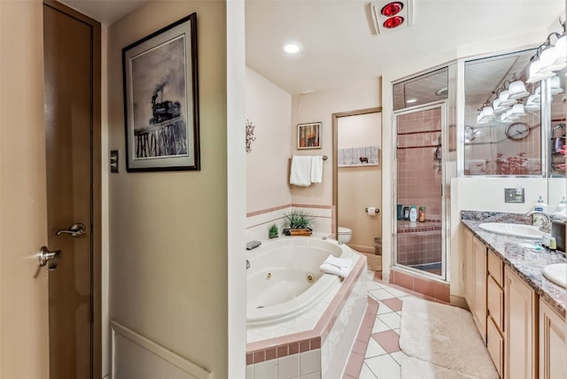 bathroom featuring double vanity, a jetted tub, toilet, a sink, and a stall shower