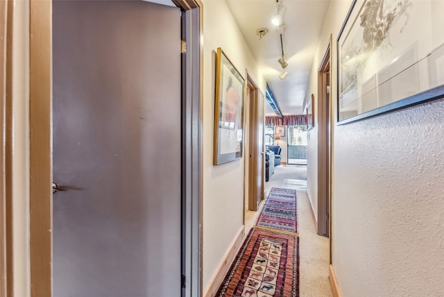 hallway featuring baseboards and carpet
