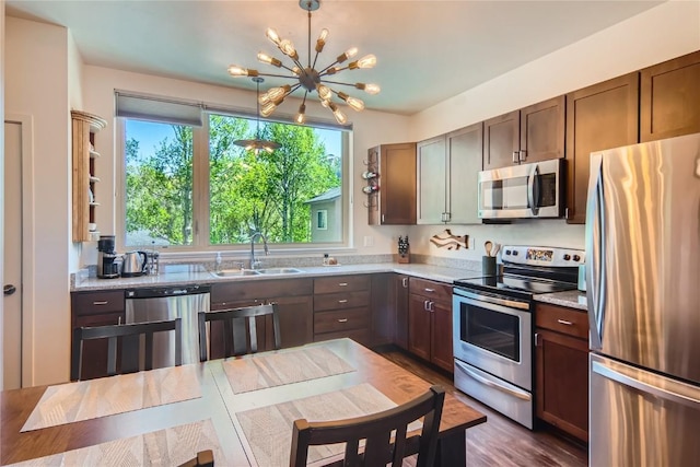 835 Weiss Cir Unit 2, Steamboat Springs, CO 80487 - kitchen featuring appliances with stainless steel finishes, a sink, a chandelier, light stone counters, and dark wood finished floors