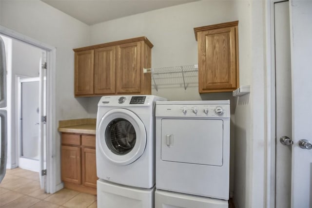 clothes washing area featuring light tile patterned flooring, cabinet space, and washer and dryer