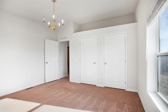 unfurnished bedroom featuring an inviting chandelier, carpet flooring, and visible vents