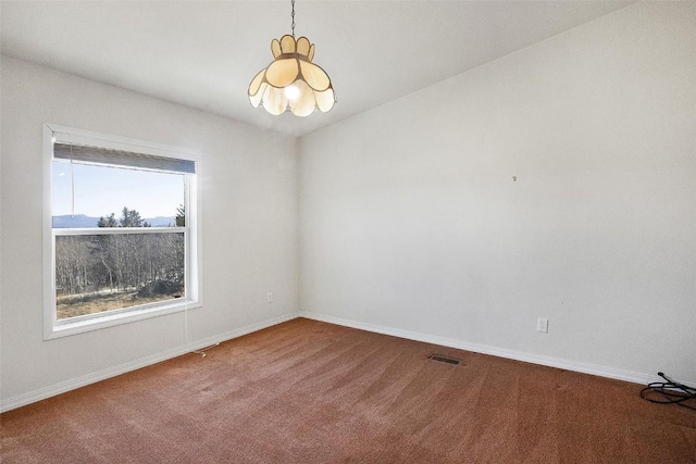 empty room featuring baseboards, carpet flooring, a chandelier, and visible vents