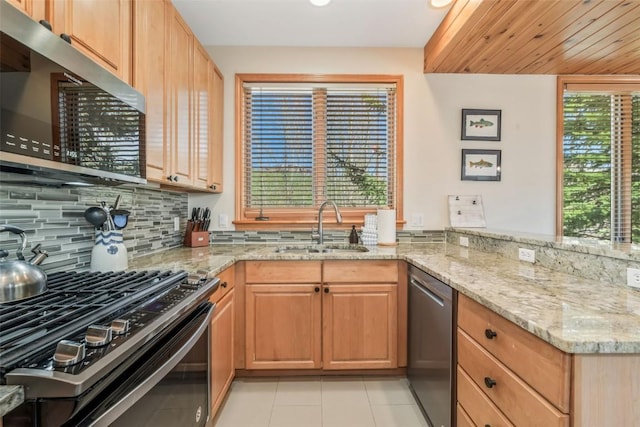 kitchen featuring light stone countertops, a sink, stainless steel appliances, decorative backsplash, and light tile patterned floors