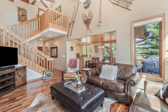 living room featuring baseboards, a high ceiling, wood finished floors, and stairway