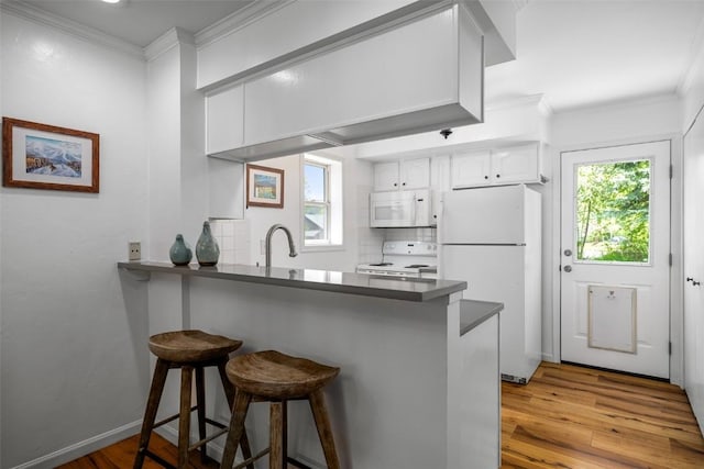 3100 Chinook Ln Unit 6, Steamboat Springs, CO 80487 - kitchen featuring white appliances, a peninsula, wood finished floors, white cabinetry, and dark countertops