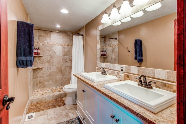 bathroom with toilet, visible vents, a sink, and a tile shower