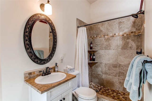 bathroom featuring vanity, toilet, and tiled shower