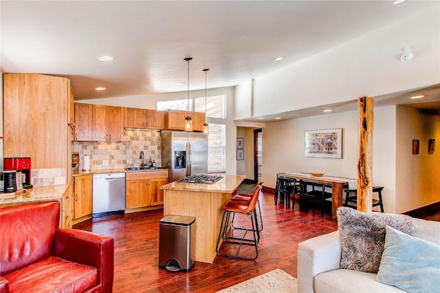 kitchen featuring lofted ceiling, a kitchen breakfast bar, a sink, a kitchen island, and appliances with stainless steel finishes