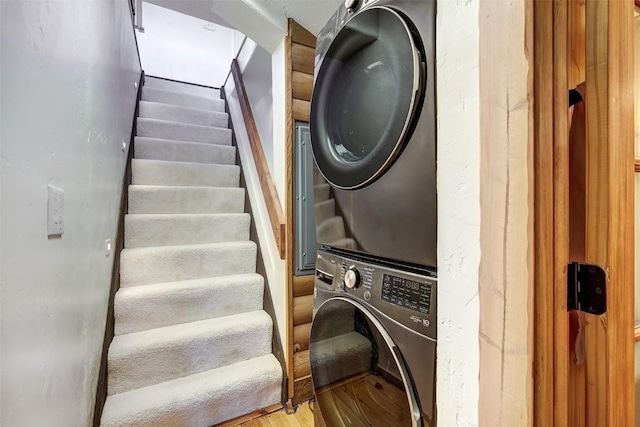 washroom with light hardwood / wood-style floors and stacked washing maching and dryer