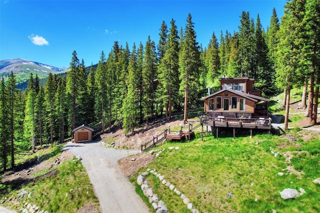 view of yard featuring a garage, an outbuilding, and a deck with mountain view