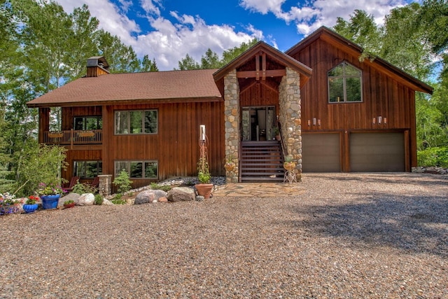 view of front of home featuring a garage, stone siding, a chimney, a shingled roof, and driveway