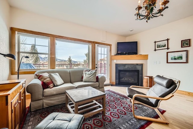 living area with a glass covered fireplace, wood finished floors, and a notable chandelier