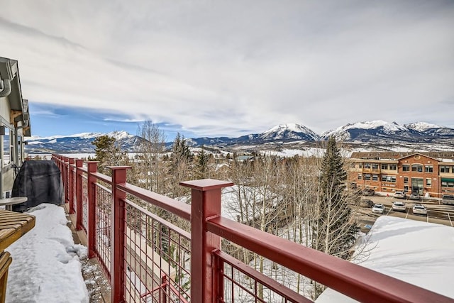 snow covered back of property featuring a mountain view
