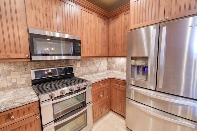 421 Rainbow Dr Unit 12, Silverthorne, CO 80498 - kitchen featuring appliances with stainless steel finishes, backsplash, light stone countertops, and light tile patterned floors
