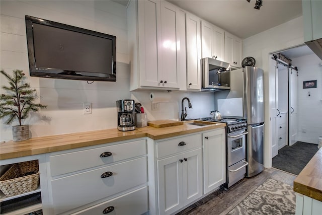 110 Sawmill Rd Unit 6B, Breckenridge, CO 80424 - kitchen with appliances with stainless steel finishes, wood counters, white cabinetry, a barn door, and a sink