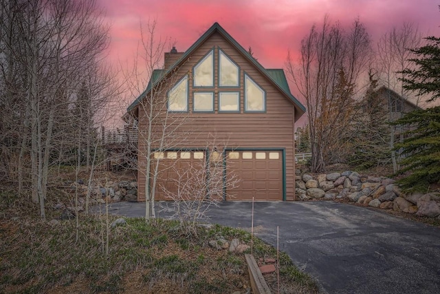 view of front of property with an attached garage, driveway, and a chimney