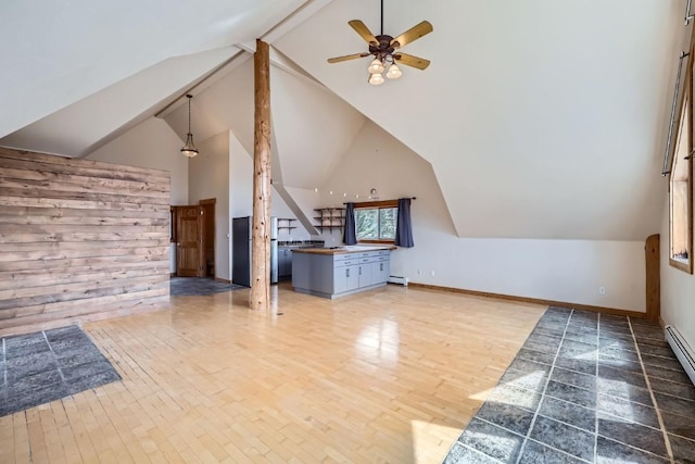 additional living space with ceiling fan, baseboards, wood finished floors, beamed ceiling, and a baseboard heating unit