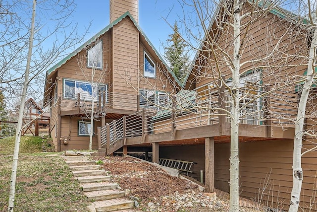 rear view of property with a wooden deck, a chimney, and stairs