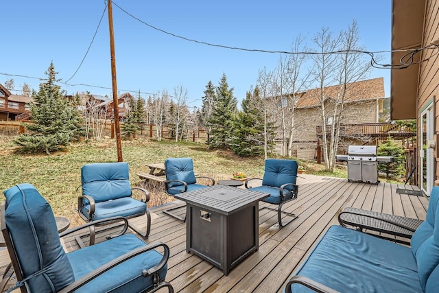 wooden deck featuring a yard, a fire pit, fence, and grilling area