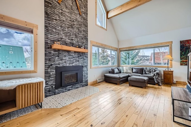 living room featuring plenty of natural light, a stone fireplace, high vaulted ceiling, beamed ceiling, and wood-type flooring