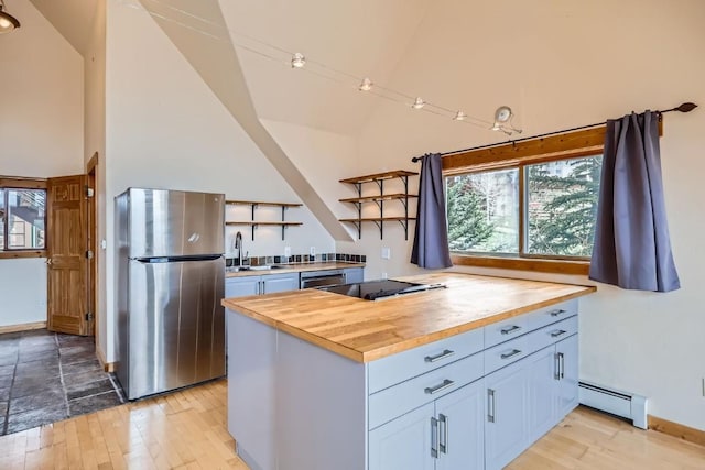kitchen featuring open shelves, butcher block counters, a baseboard heating unit, a sink, and stainless steel appliances
