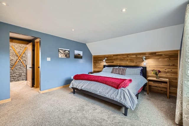bedroom with carpet floors, baseboards, lofted ceiling, and wooden walls