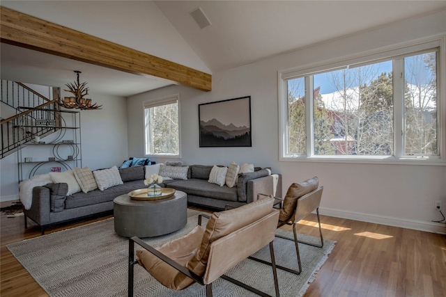 living room featuring an inviting chandelier, stairs, baseboards, and wood finished floors