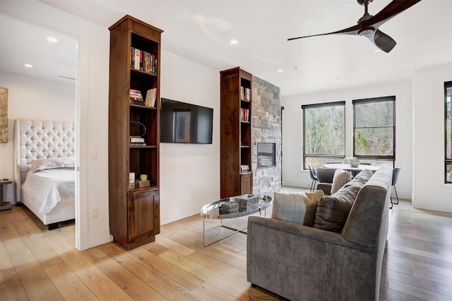 living room with a fireplace, light wood-type flooring, ceiling fan, and recessed lighting