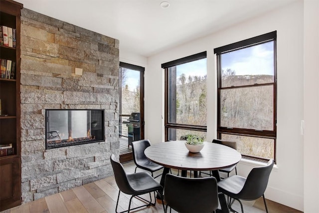 dining space featuring baseboards, wood finished floors, and a fireplace