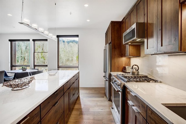 kitchen with light wood finished floors, stainless steel appliances, baseboards, and recessed lighting
