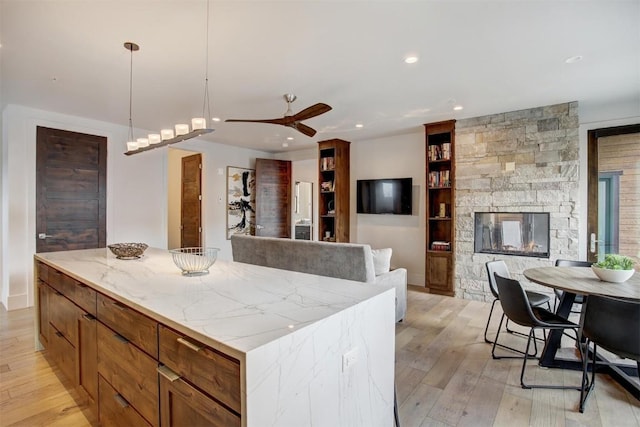 kitchen with decorative light fixtures, a ceiling fan, a center island, and light wood-style floors