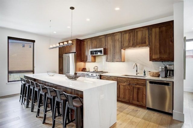 kitchen featuring light wood-type flooring, a center island, stainless steel appliances, and a sink