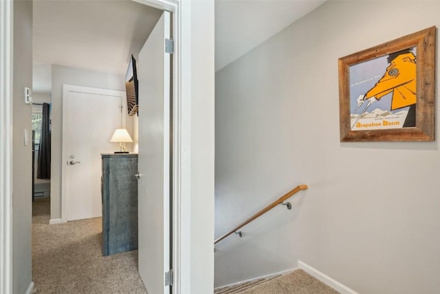 hallway with carpet, an upstairs landing, and baseboards