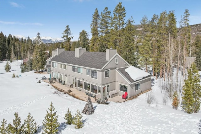 snow covered back of property featuring a chimney