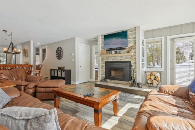 living area with a stone fireplace, a notable chandelier, and a baseboard radiator