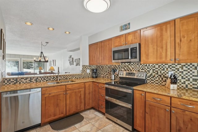 kitchen with brown cabinetry, stainless steel appliances, tasteful backsplash, and a sink