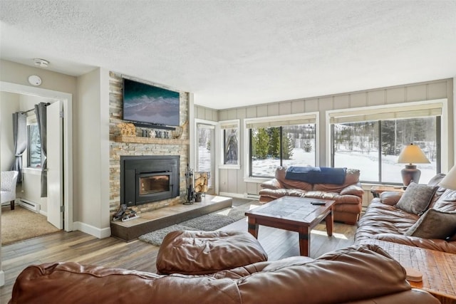 living room featuring wood finished floors, baseboards, a fireplace, a textured ceiling, and a baseboard heating unit