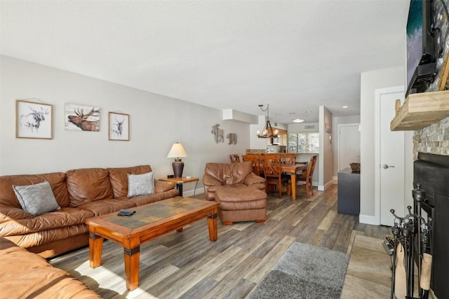 living room featuring a fireplace, baseboards, an inviting chandelier, and wood finished floors