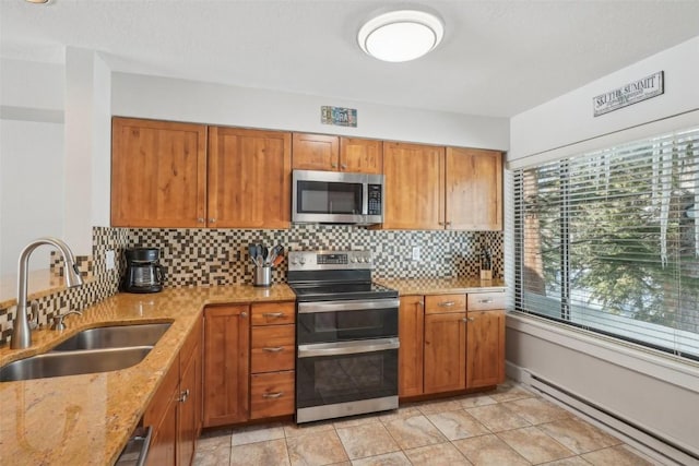 kitchen with tasteful backsplash, appliances with stainless steel finishes, light stone countertops, and a sink