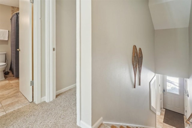 corridor with vaulted ceiling, baseboards, and carpet floors