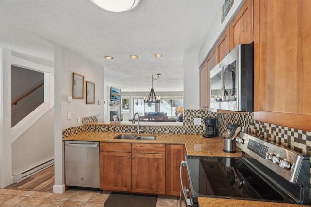 kitchen featuring brown cabinets, a sink, a baseboard heating unit, tasteful backsplash, and appliances with stainless steel finishes