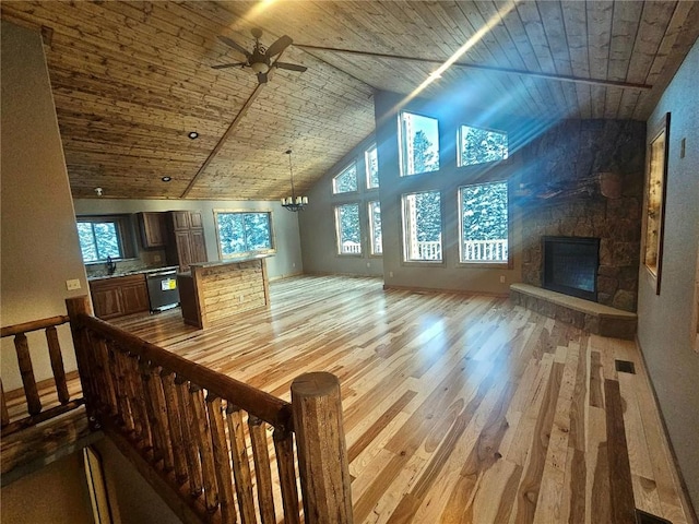 additional living space with wooden ceiling, light wood-style floors, high vaulted ceiling, a stone fireplace, and ceiling fan with notable chandelier