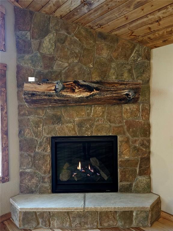 room details featuring wooden ceiling, baseboards, wood finished floors, and a fireplace