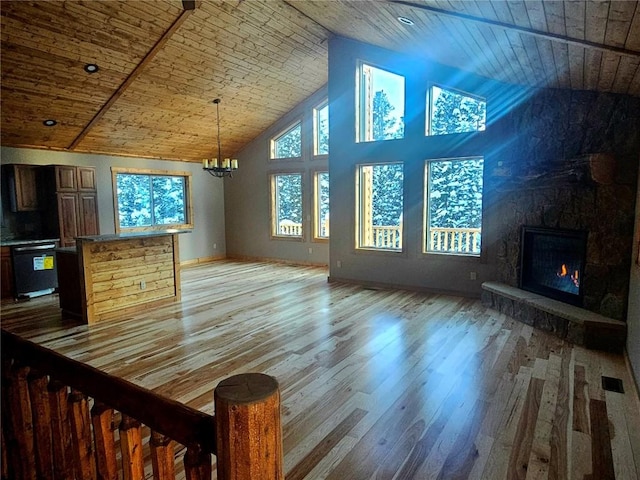 unfurnished living room with light wood-type flooring, wooden ceiling, a notable chandelier, and high vaulted ceiling