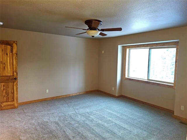 unfurnished room featuring light colored carpet, ceiling fan, baseboards, and a textured ceiling