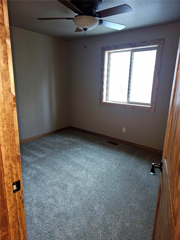 spare room with carpet, visible vents, a ceiling fan, and baseboards