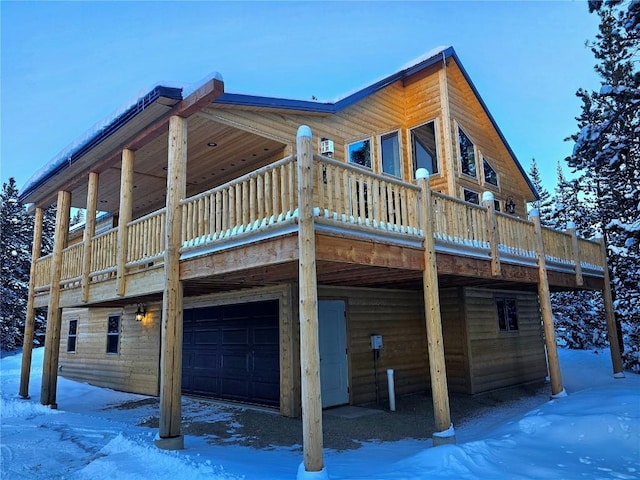 view of snowy exterior with a wooden deck and a garage