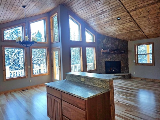 kitchen with light wood finished floors, a notable chandelier, brown cabinetry, and wood ceiling